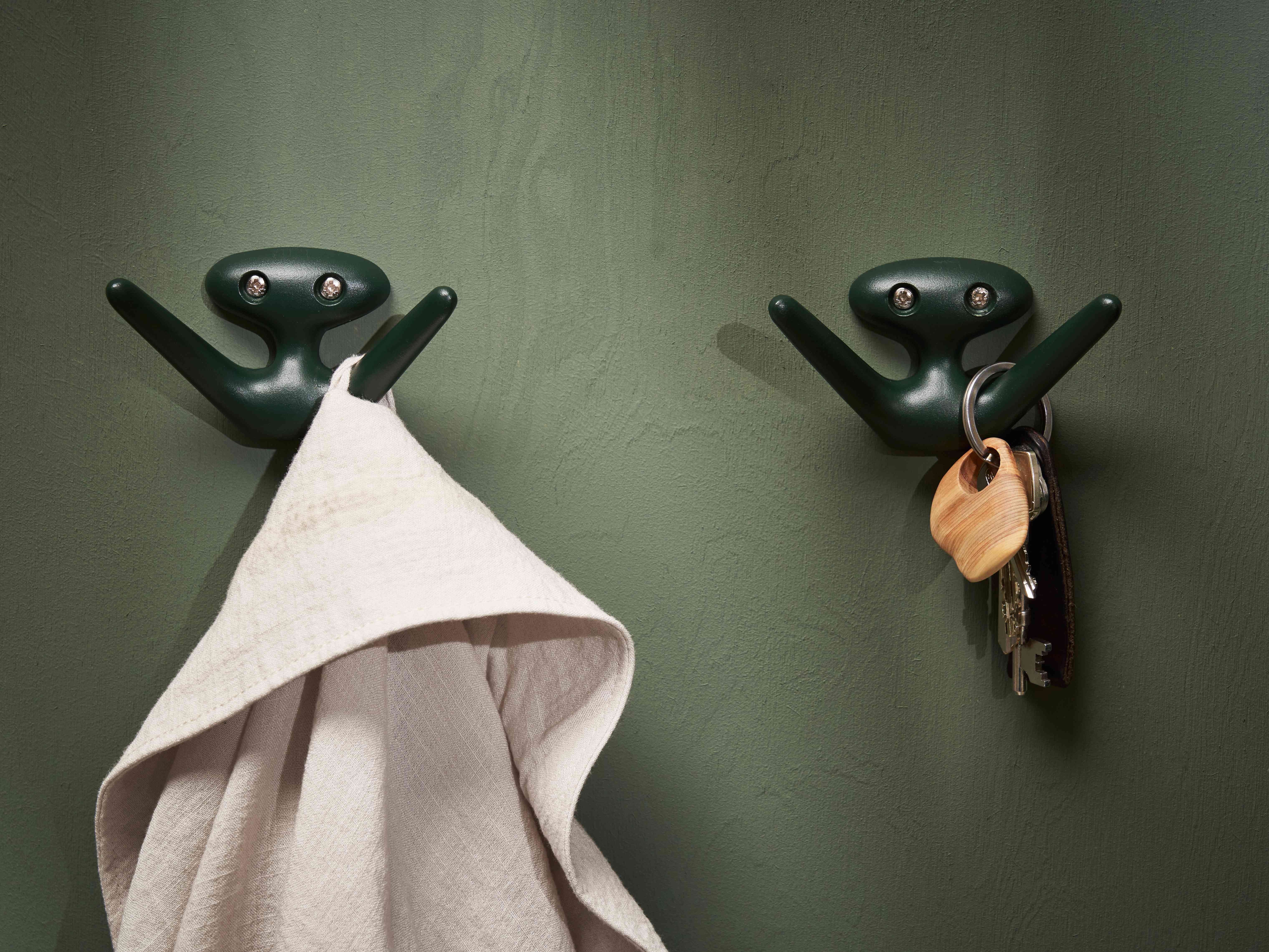 The Mama hook in a fir green color on a green wall support both clothes and keys. 